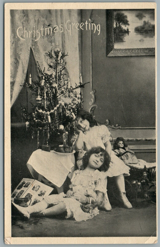 LITTLE SISTERS w/ DOLLS UNDER CHRISTMAS TREE ANTIQUE POSTCARD