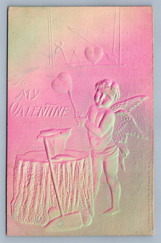 VALENTINE ANTIQUE DEEPLY EMBOSSED POSTCARD CUPID HAMMERING THE HEART